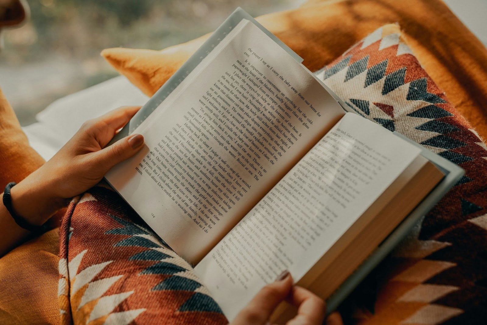 Vrouw die boek leest onder een dekentje met aztekenprint