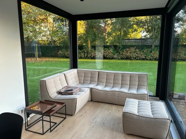 Beige hoekzetel en houten salontafeltjes in modulaire unit